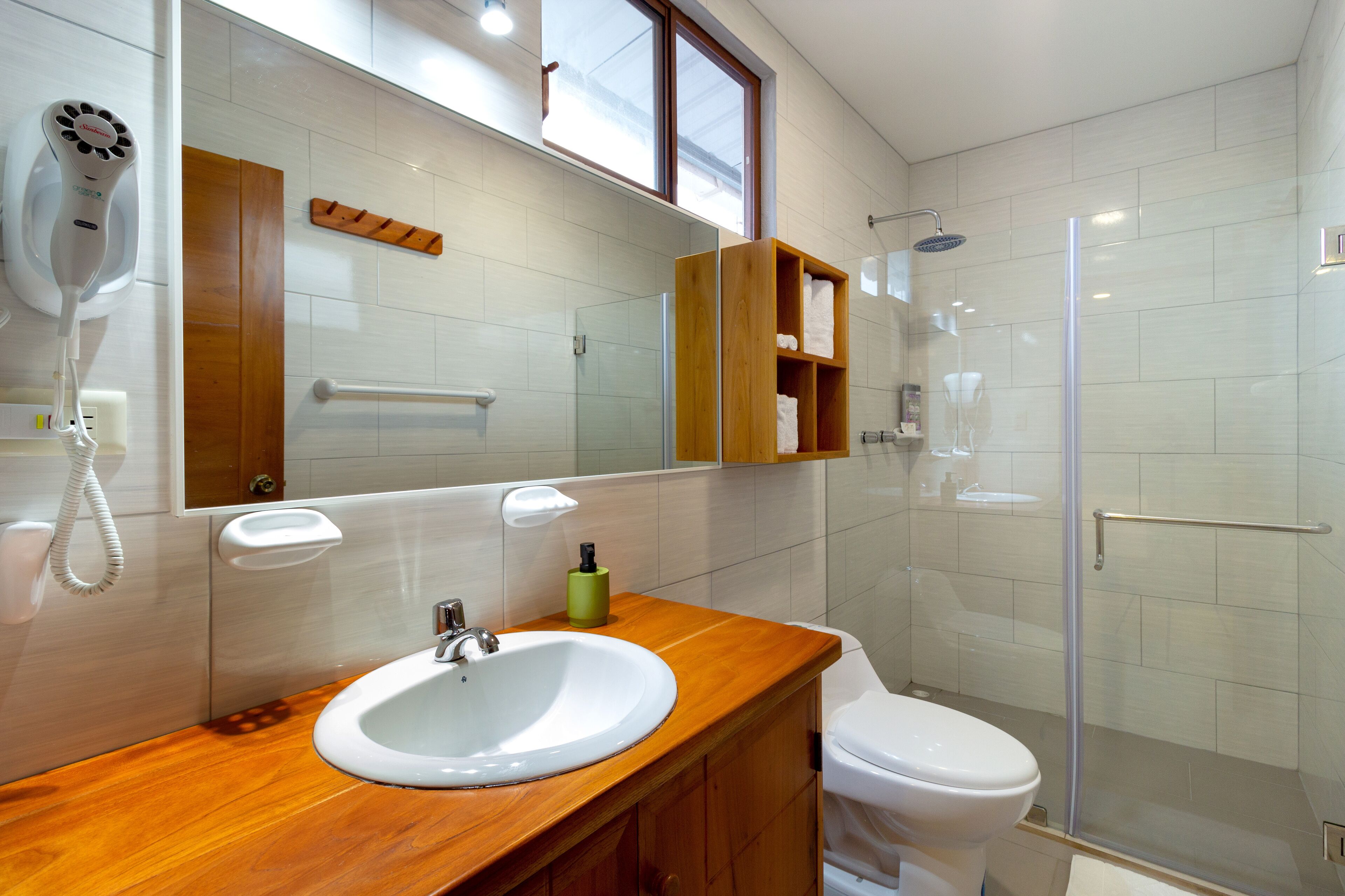 A modern bathroom with a wooden vanity, a white sink, a glass shower enclosure, and a toilet.
