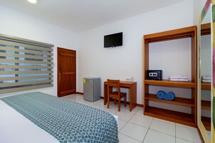 Une chambre d’hôtel comprenant un lit, un bureau avec une chaise, une télévision, une armoire et un petit réfrigérateur.