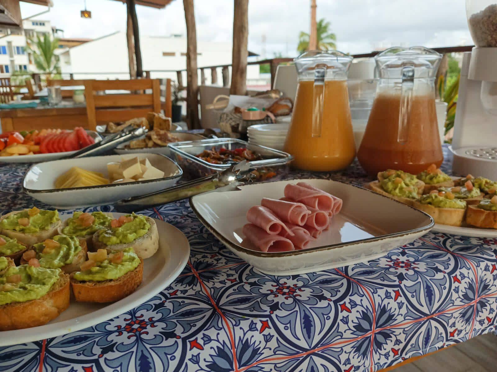 Een ontbijtbuffet met diverse gerechten, waaronder avocado toast, ham en vruchtensappen.