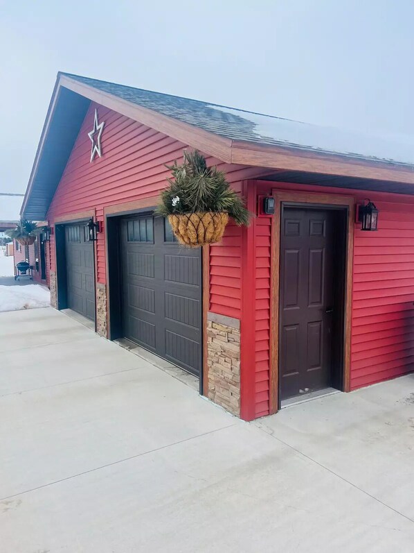 A red building with two garage doors, a hanging planter with greenery, and a star on the wall.