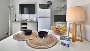 A modern kitchen with white cabinets, a microwave, a refrigerator, and a flat-screen TV mounted on the wall. - Le Moulin de la Filasse by Interhome (Ile d'Oléron)