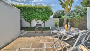 A patio with a table and chairs, a grill, and a tree with green foliage. - Le Moulin de la Filasse by Interhome (Ile d'Oléron)