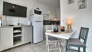A modern kitchen with a flat-screen TV, a white refrigerator, and a dining area with a table and chairs. - Le Moulin de la Filasse by Interhome (Ile d'Oléron)