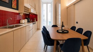 A modern kitchen with a dining area, featuring a wooden table, blue chairs, and a wine bottle.
