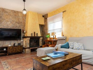 Ein Wohnzimmer mit Steinspeicher, Kamin, Sofa, Couchtisch und Fernseher.