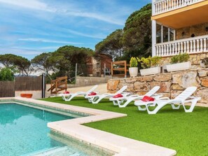 A swimming pool with white lounge chairs and a stone wall. - Armonia by Interhome (Tordera)