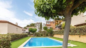 Une piscine entourée de pelouses et de haies bien entretenues, avec des immeubles d’habitation en arrière-plan.