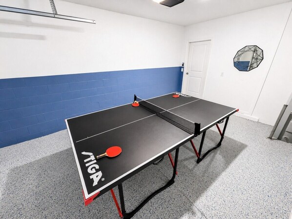 A ping pong table with two paddles, a door, and a wall with a blue stripe.