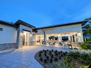 A modern building with a covered patio area, outdoor seating, and a landscaped garden.