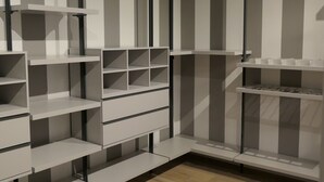 Een moderne, minimalistische kast met meerdere planken en hangruimte, met een houten vloer.