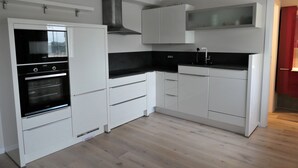 Een moderne keuken met witte kastjes, een zwart aanrecht en een inbouwoven.