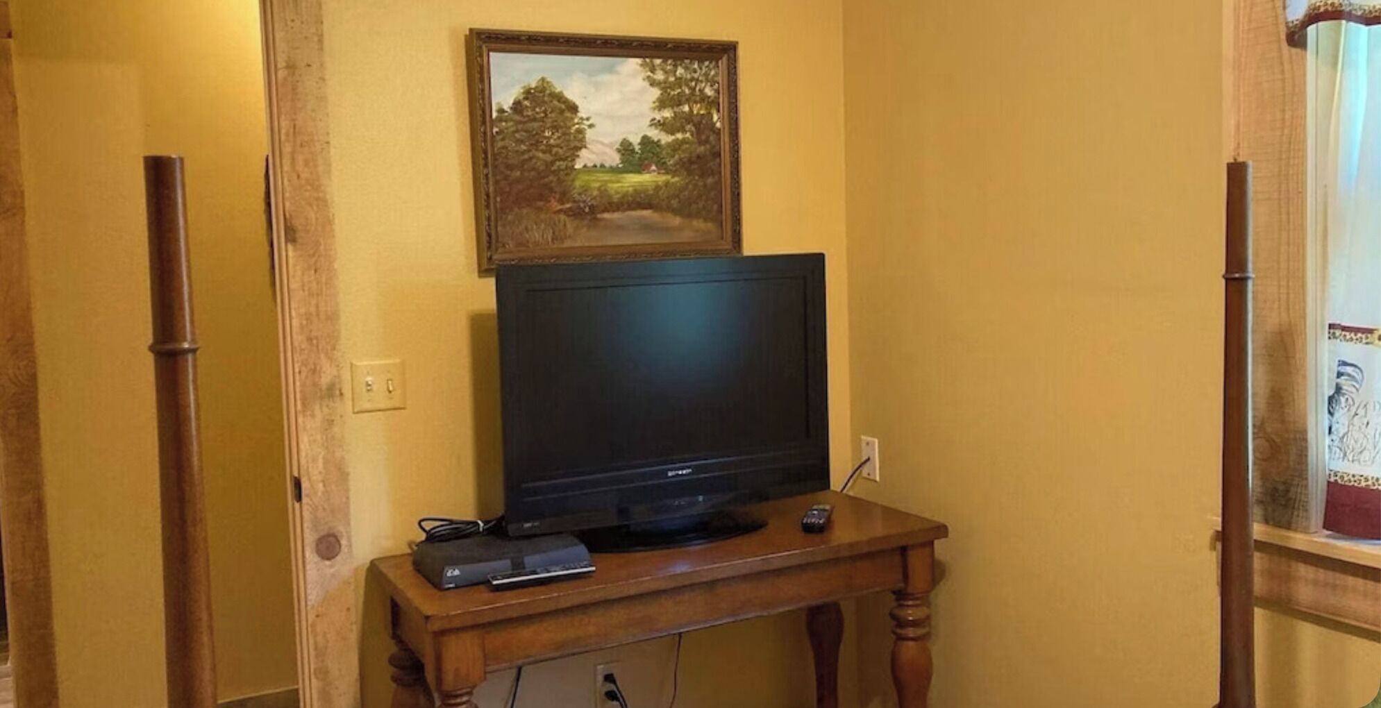 Un téléviseur posé sur un meuble en bois, avec un tableau accroché au-dessus.