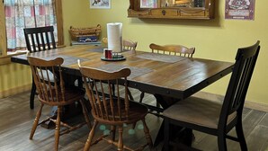 Une table à manger avec quatre chaises en bois, un rouleau d’essuie-tout et un petit panier posé sur la table.