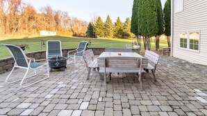 An outdoor patio with a stone floor, a wooden table, and four chairs. - Red Fox Run Hideaway (Victor)