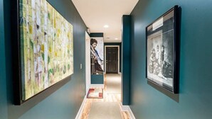 A hallway with teal walls, a wooden floor, and framed pictures on the walls. - Red Fox Run Hideaway (Victor)