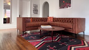 A modern living room with a brown sectional sofa, a round coffee table, and a patterned rug. - Artisan Gem - 2 BR / 1 Bath (Spruce Pine)
