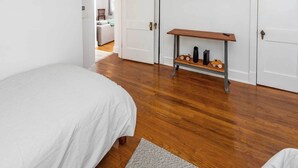 A bedroom with a bed, a TV mounted on the wall, and a small wooden table with decorative items. - Artisan Gem - 2 BR / 1 Bath (Spruce Pine)