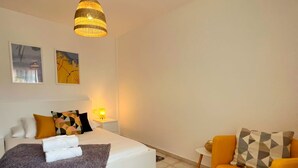 Ein Schlafzimmer mit einem Bett, einem Sofa, einem Teppich und einer Pendelleuchte.