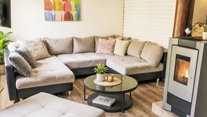 A modern living room with a sectional sofa, a round coffee table, and a wood-burning stove. - Rumpelstilzchen by Interhome (Frankenau)