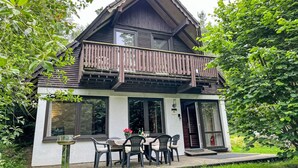 A two-story house with a balcony, a dining area with chairs and a table, and a small garden. - Rumpelstilzchen by Interhome (Frankenau)