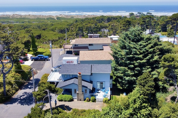 Aerial view of house with dunes and beach in background.