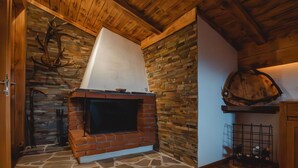 Una chimenea de piedra con revestimiento de ladrillo, vigas de madera en el techo y suelo de piedra.
