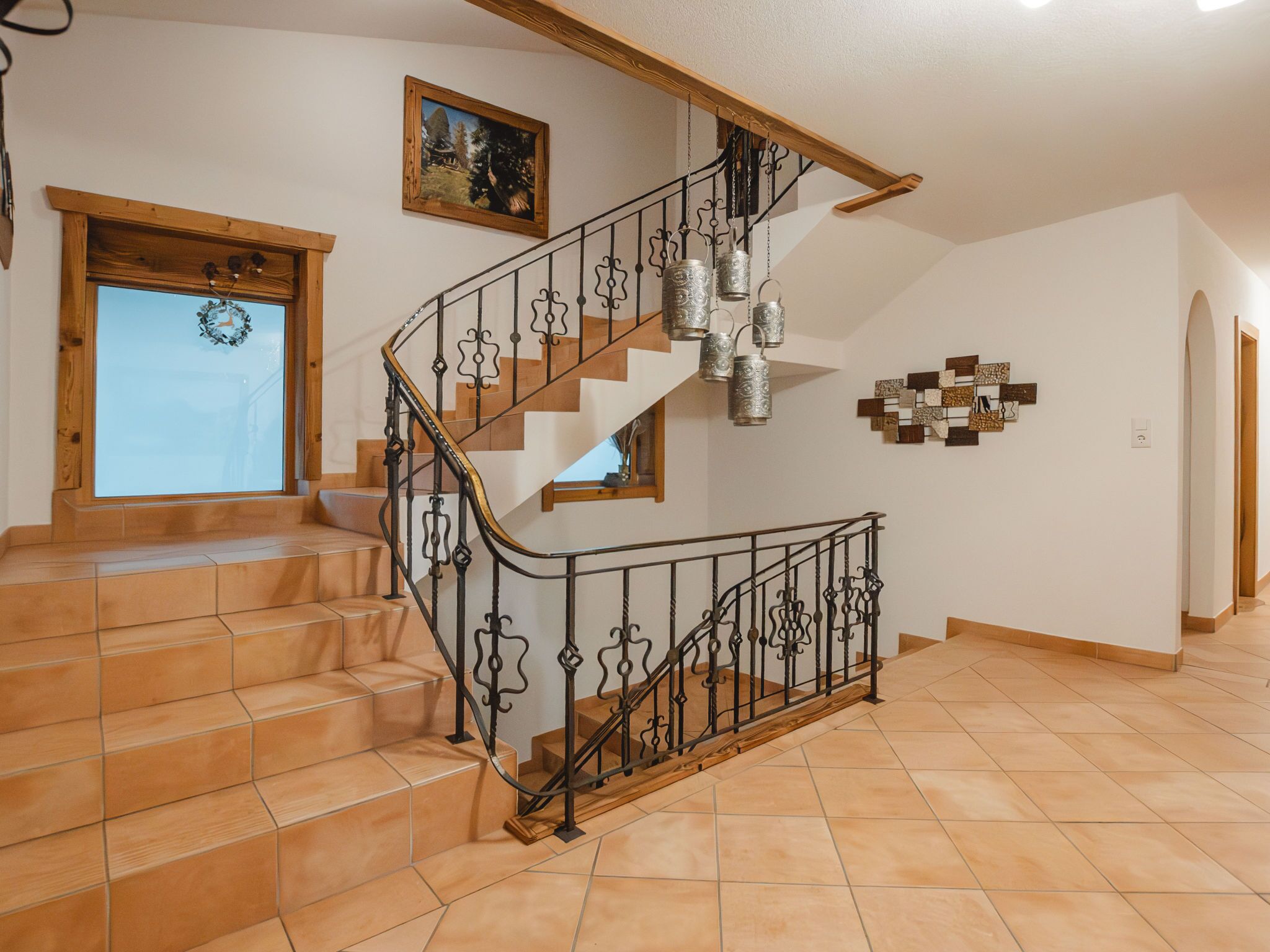 A staircase with a wrought iron railing, wooden steps, and a wall-mounted picture.