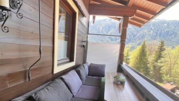 Un interior de madera con un sofá y una ventana con vistas a un paisaje montañoso.
