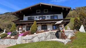 Un chalet de dos plantas con techo inclinado, ventanas grandes y cimientos de piedra.