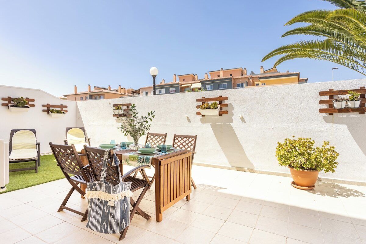 A patio with a table and chairs, a potted plant, and a view of neighboring buildings.