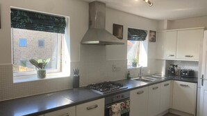 Une cuisine moderne avec des armoires blanches, une cuisinière à gaz et une hotte en acier inoxydable.