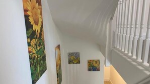 Un escalier avec des rampes blanches et un mur orné de trois tableaux représentant des tournesols.