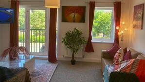 Un salon avec un canapé, une table basse, une plante en pot et un tableau accroché au mur.