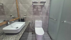 A bathroom with a white sink, a toilet, a towel rack, and a shower.