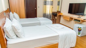 A hotel room with two beds, a TV, a minibar, and a wooden wardrobe.
