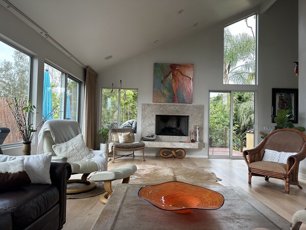 Un salón comedor amplio con chimenea, ventanas grandes y vistas a la naturaleza.