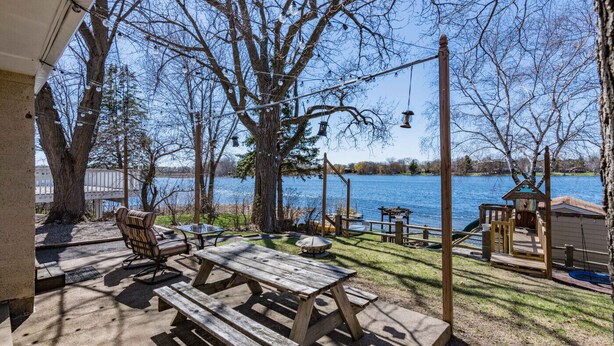 An outdoor patio with picnic tables and chairs, overlooking a lake. - Lakefront Family Beach House (Andover)
