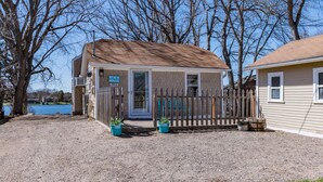 A single-story house with a fenced front yard, a small porch, and a visible garage door. - Lakefront Family Beach House (Andover)