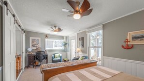 A bedroom with a large bed, a desk, a chair, and a ceiling fan. - Lakefront Family Beach House (Andover)