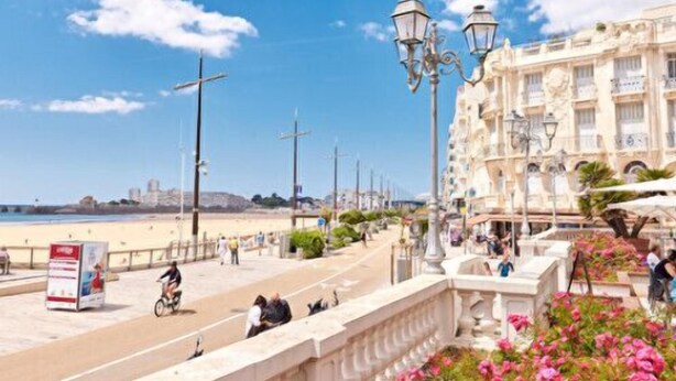A coastal promenade with a beach, street lamps, and a building with balconies. - Duplex near the beach (Les Sables-d'Olonne)