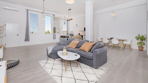A modern living room with a grey sofa, a coffee table, and a dining area with a table and chairs. - Homey Apt. Cómpeta (Málaga)