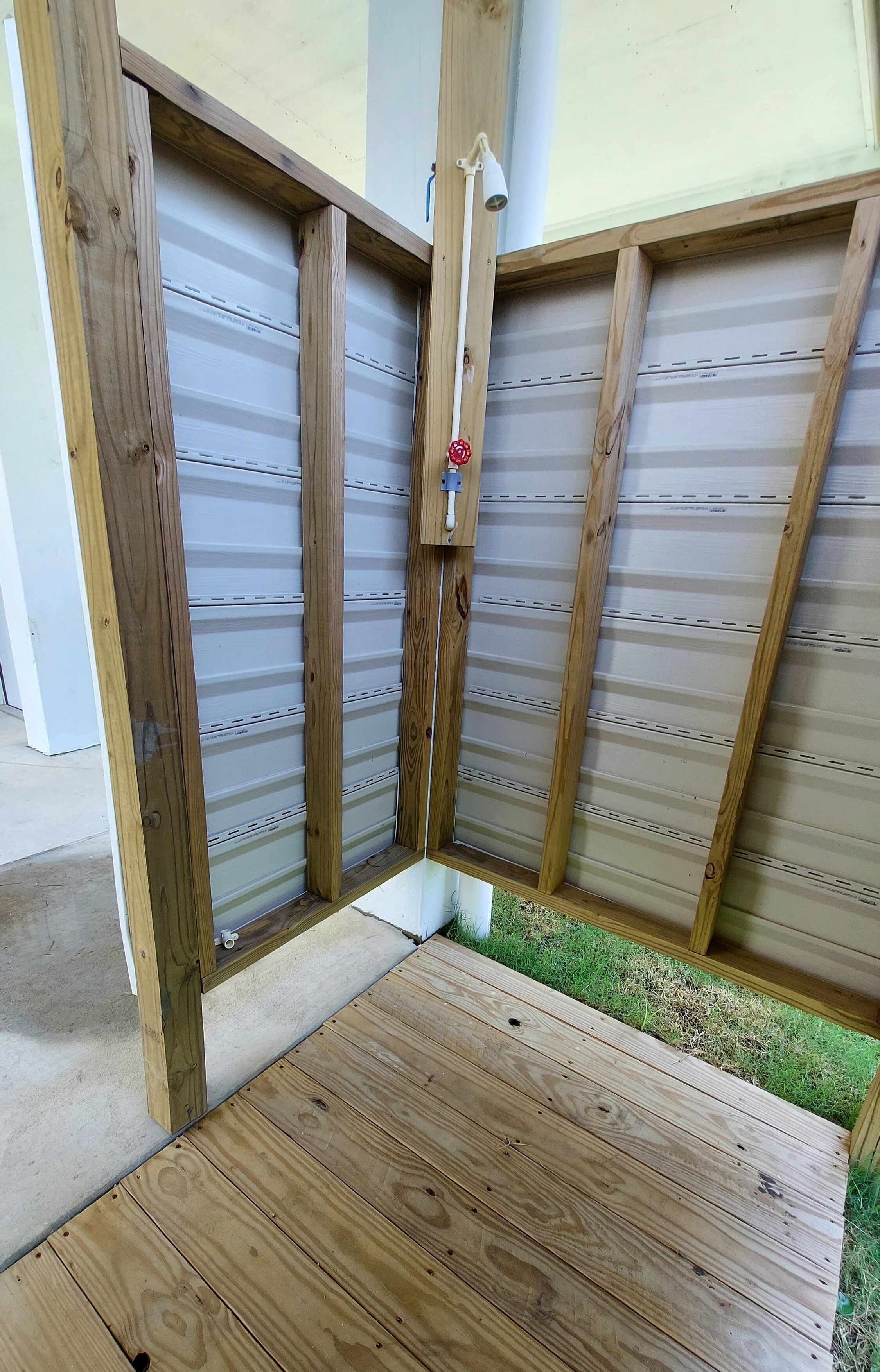A wooden deck with a metal gate and a small concrete step leading to a grassy area.