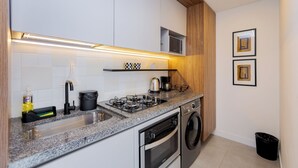Cuina moderna amb armaris blancs, tauleig de granit, microones integrat, forlla de gas i rentadora.