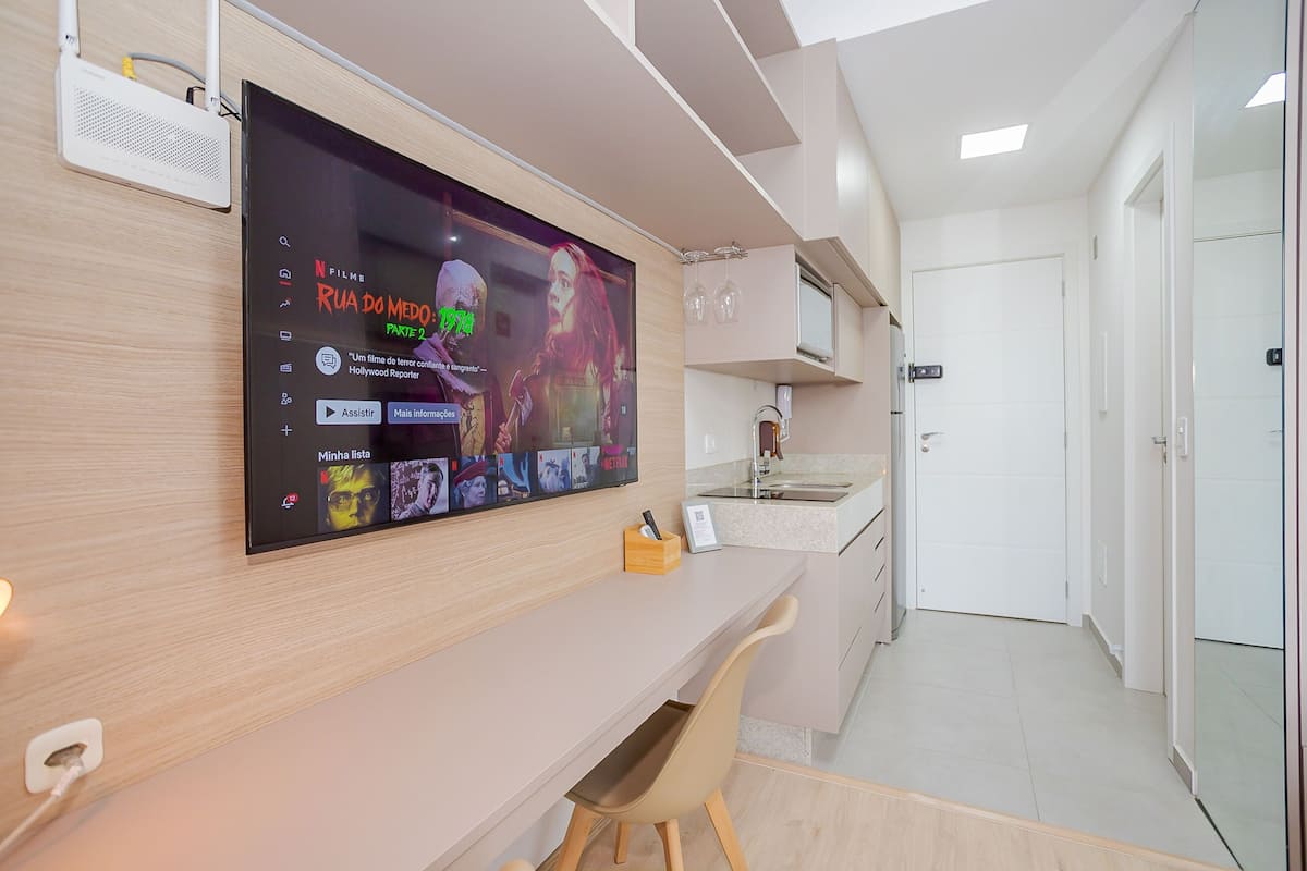 A modern room with a large flat-screen TV mounted on the wall displaying a Netflix interface.
