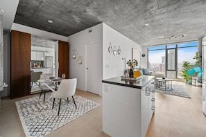 Um apartamento moderno com cozinha, área de refeições e sala de estar, com grandes janelas e vista para a cidade.