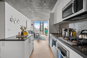 Uma cozinha moderna com uma janela ampla, uma área de refeições com vista e um espaço de estar com vista para a cidade.