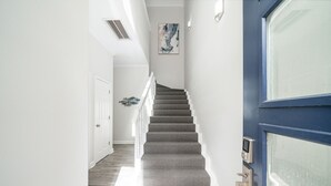 Una escalera de diseño moderno que lleva a una puerta con un panel de seguridad.