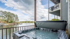 Un jacuzzi con vista a un lago y un muelle, un balcón y una terraza de madera.