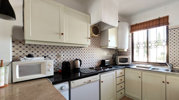 A compact kitchen with white cabinets, a microwave, a toaster, and a kettle. - São Rafael Duplex by Rentals in Algarve (Albufeira)