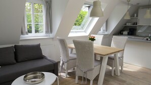 A modern loft apartment with a dining area, a sofa, and a kitchen. - Vacation apartment Odde (Nebel)